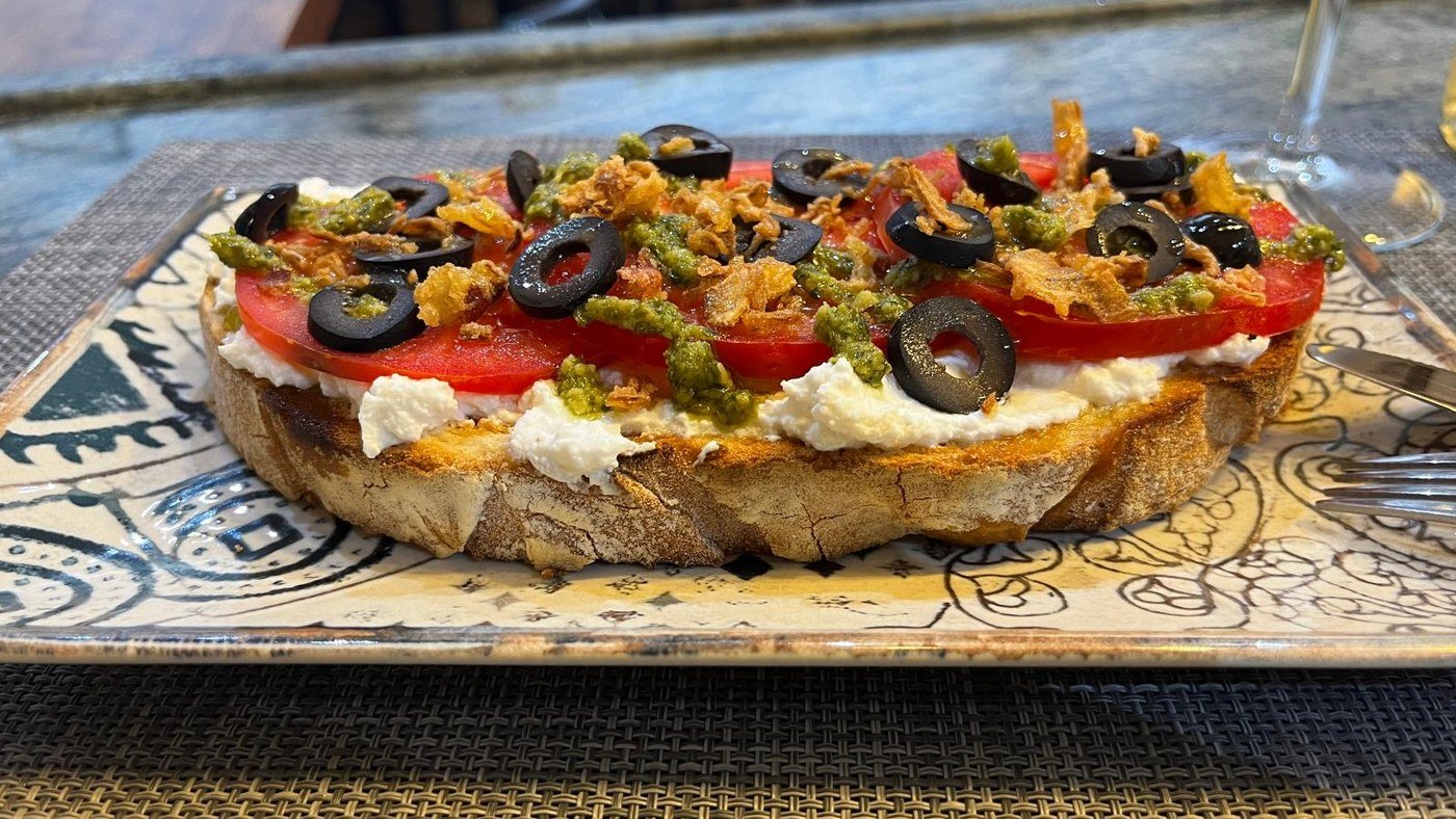 Tosta de ricotta con tomate, pesto y aceitunas negras